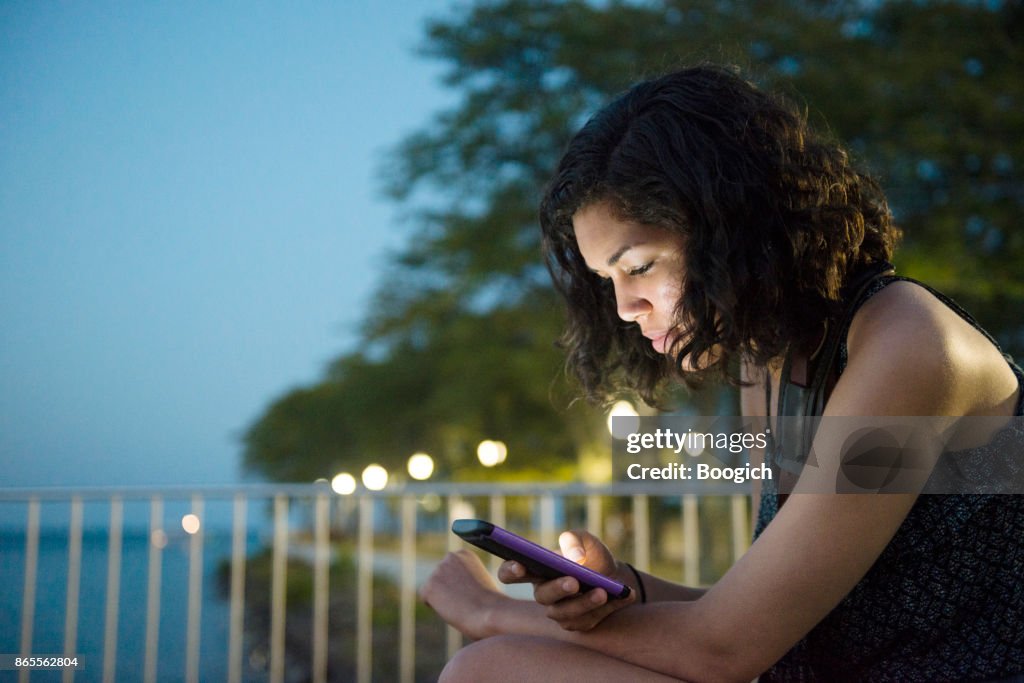 Millennial Hispanic Woman On Social Media in Chicago Park Night