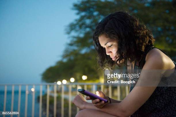 millennial hispanic woman on social media in chicago park night - hot puerto rican women stock pictures, royalty-free photos & images