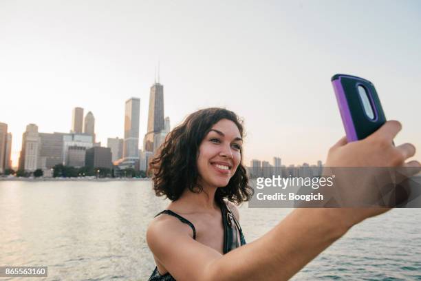 millennial hispanic woman takes selfie at chicago skyline - hot puerto rican women stock pictures, royalty-free photos & images