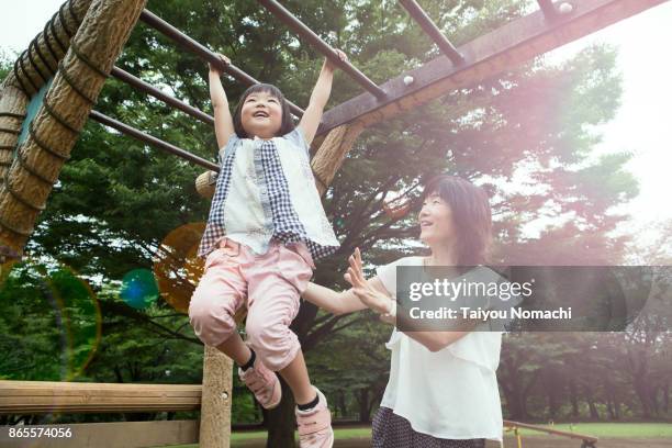 mother and daughter playing in the park - speeltuintoestellen stockfoto's en -beelden