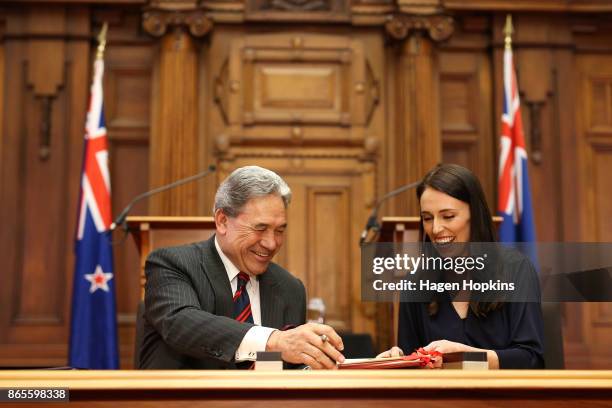 Prime Minister-designate Jacinda Ardern and NZ First leader Winston Peters exchange documents during a coalition agreement signing at Parliament on...