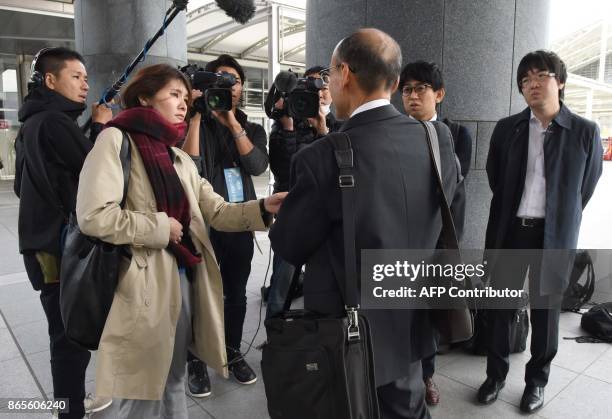 Journalists interview a shareholdetr before an extraordinary shareholders meeting of Toshiba in Chiba, suburb of Tokyo, on October 24, 2017....