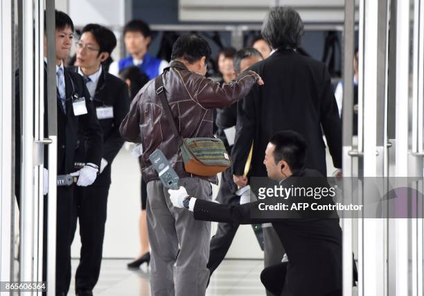 Staff members check belongings at the entrance of an extraordinary shareholders meeting of Toshiba in Chiba, suburb of Tokyo, on October 24, 2017....