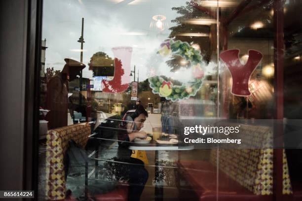 Customer uses a smart phone while dining inside a Jollibee Foods Corp. Restaurant in the Bonifacio Global City triangle area of Manila, the...