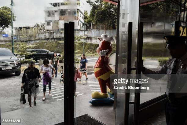 Security guard holds the door for approaching customers at a Jollibee Foods Corp. Restaurant in the Bonifacio Global City triangle area of Manila,...