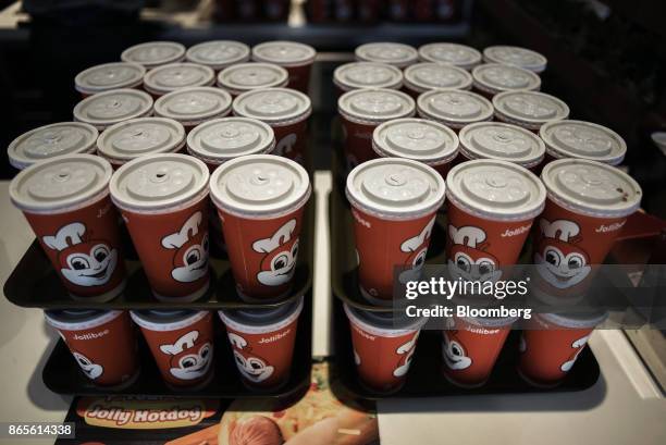 Paper cups containing cold beverages sit stacked up on a counter at a Jollibee Foods Corp. Restaurant in the Bonifacio Global City triangle area of...