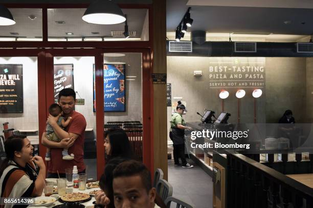 Customers dine at a Greenwich Pizzeria, operated by Jollibee Foods Corp., in the Bonifacio Global City triangle area of Manila, the Philippines, on...