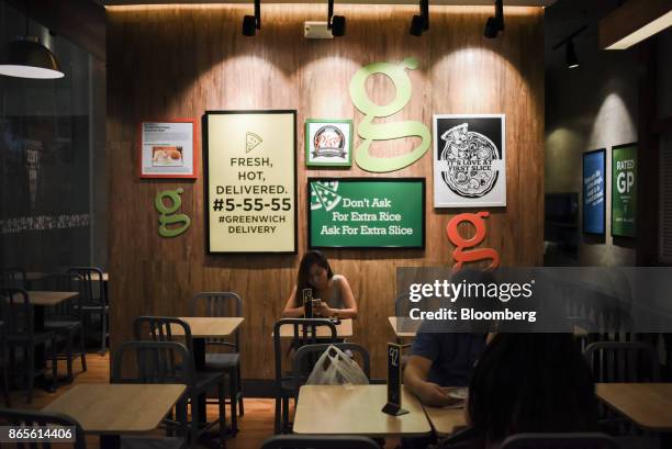 Customers sit at a Greenwich Pizzeria, operated by Jollibee Foods Corp., in the Bonifacio Global City triangle area of Manila, the Philippines, on...