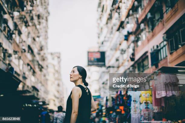 young woman looking far away in city with local street scene in hong kong - prosperity stock pictures, royalty-free photos & images