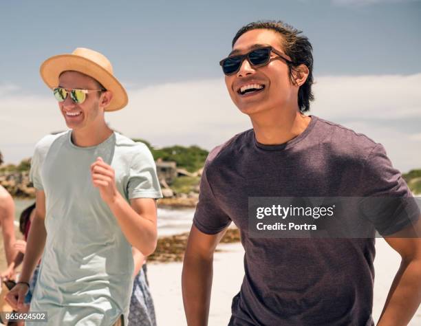 cheerful young man with friend at beach - só homens jovens imagens e fotografias de stock