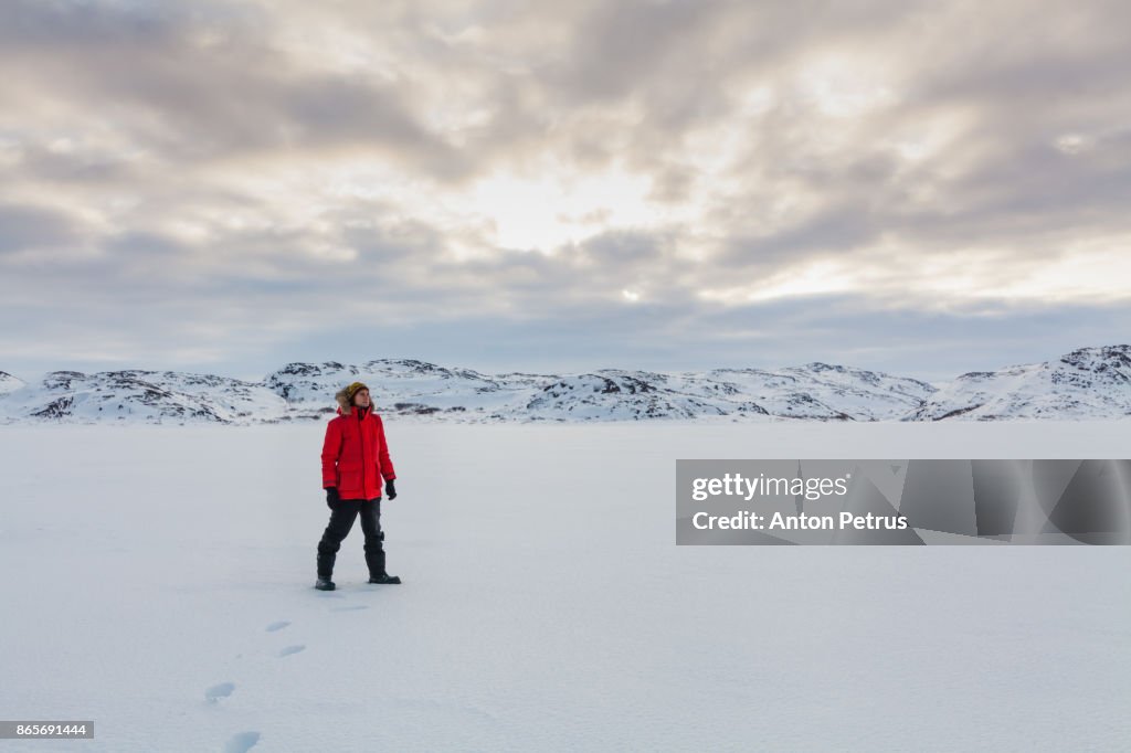 Young man in the snowy tundra at sunset