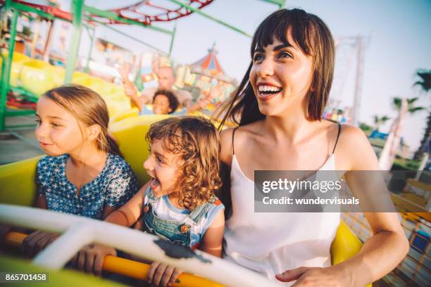 excited son and daughter with mother on roller coaster ride - theme park ride stock pictures, royalty-free photos & images