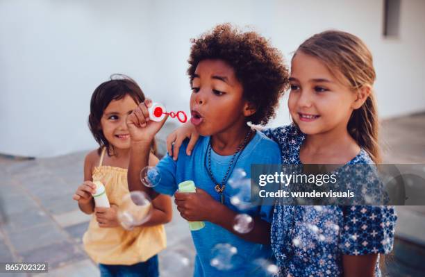 beste vrienden multi-etnische kinderen bellen blazen op zomervakantie - child blowing bubbles stockfoto's en -beelden