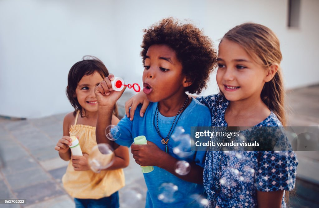 Multi-ethnic children best friends blowing bubbles on summer holidays