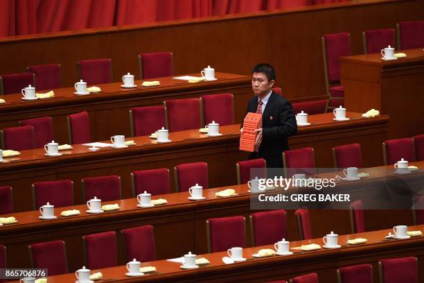 An attendant clears name cards used by Chinese leaders after the closing of the 19th Communist Party Congress at the Great Hall of the People in...