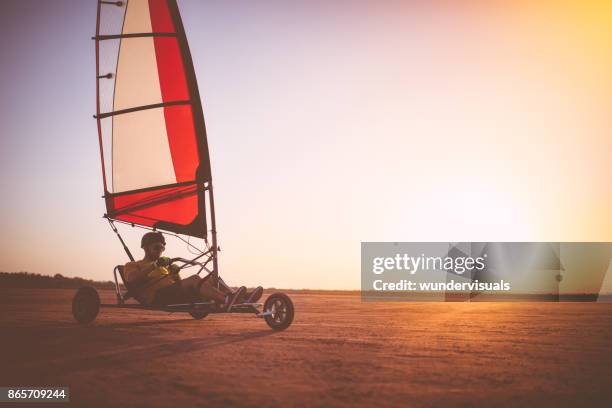 man van drijvende land zeilen blokart op het strand bij zonsondergang - zeilwagen stockfoto's en -beelden