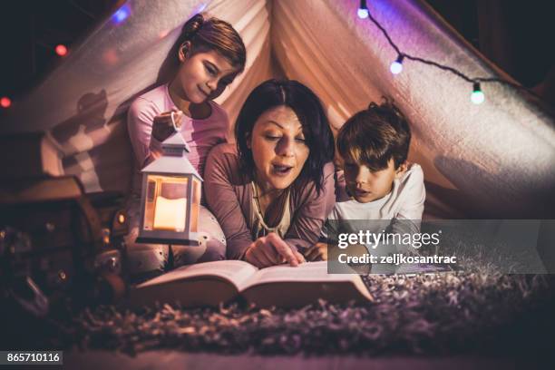 gelukkige familie moeder en kind lezen van een boek in de tent thuis - ronnie corbett signs copies of his book and its goodnight from him at stockfoto's en -beelden