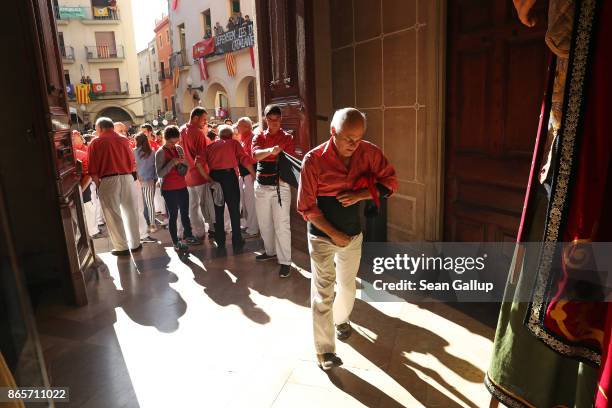 An older member of the pink team gets help in putting on his tightly-fitting "faixa," a sash the human tower team members, called "castellers," use...