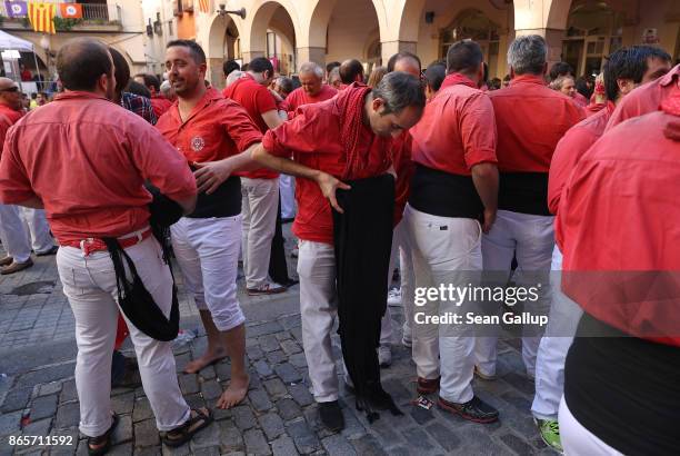 Member of the red team rolls up his "faixa," a sash the human tower team members, called "castellers," use to protect their lower back and provide a...