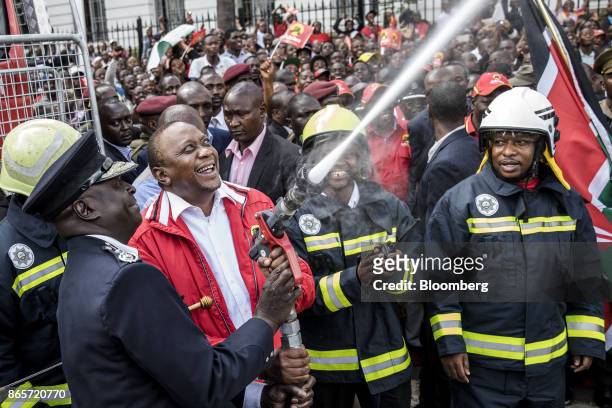 Uhuru Kenyatta, Kenya's president, second left, sprays a water hose during a ceremony to inaugurate new fire engines for the Nairobi County...