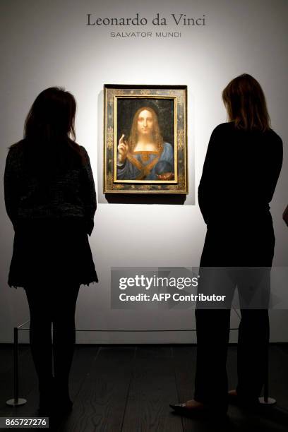 Christie's employees pose in front of a painting entitled Salvator Mundi by Italian polymath Leonardo da Vinci at a photocall at Christie's auction...