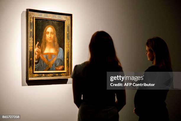 Christie's employees pose in front of a painting entitled Salvator Mundi by Italian polymath Leonardo da Vinci at a photocall at Christie's auction...