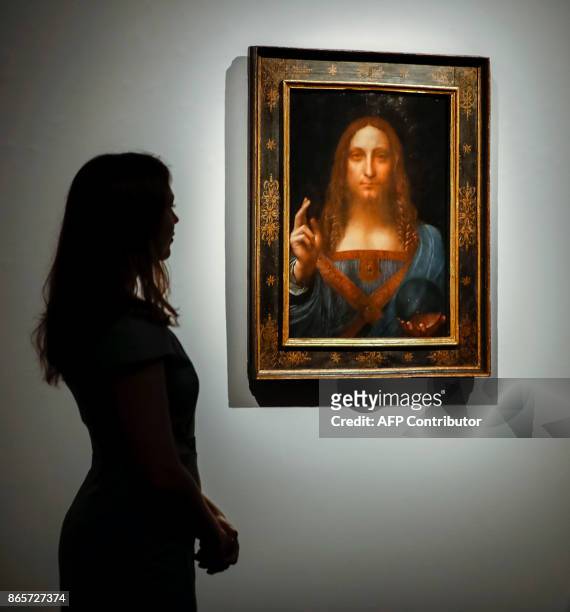 Christie's employees pose in front of a painting entitled Salvator Mundi by Italian polymath Leonardo da Vinci at a photocall at Christie's auction...