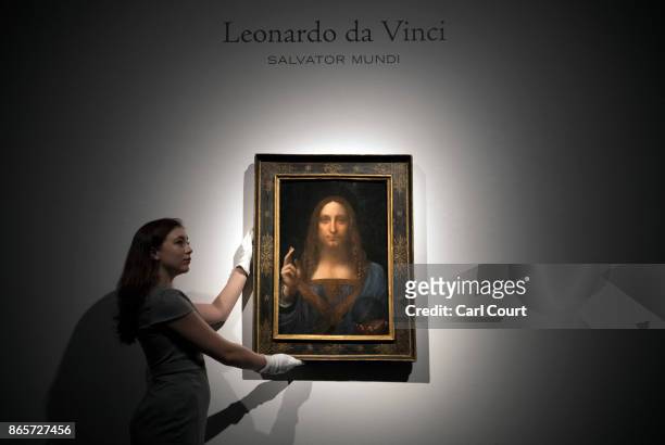 Member of staff poses with a painting by Leonardo da Vinci entitled 'Salvator Mundi' before it is auctioned in New York on November 15, at Christies...