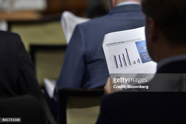 An attendee looks at company information documents during a Saab AB earnings news conference in Stockholm, Sweden, on Tuesday. Oct. 24, 2017. Saab...
