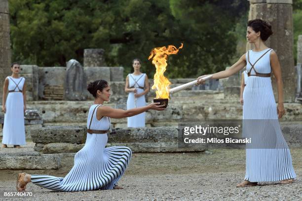 High priestess passes the Olympic flame at the Temple of Hera during a lighting ceremony of the Olympic flame in ancient Olympia on October 24, 2017...