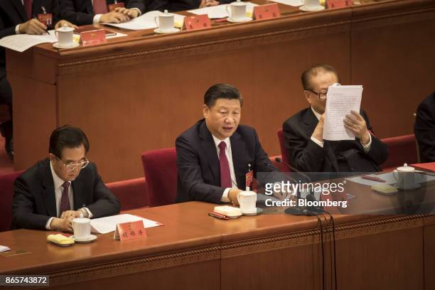 Xi Jinping, China's president, center, speaks as Jiang Zemin, China's former president, right, reads a document while Hu Jintao, China's former...