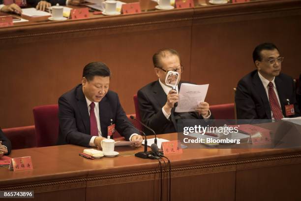 Xi Jinping, China's president, left, speaks as Jiang Zemin, China's former president, center, uses a magnifying glass to read a document while Li...