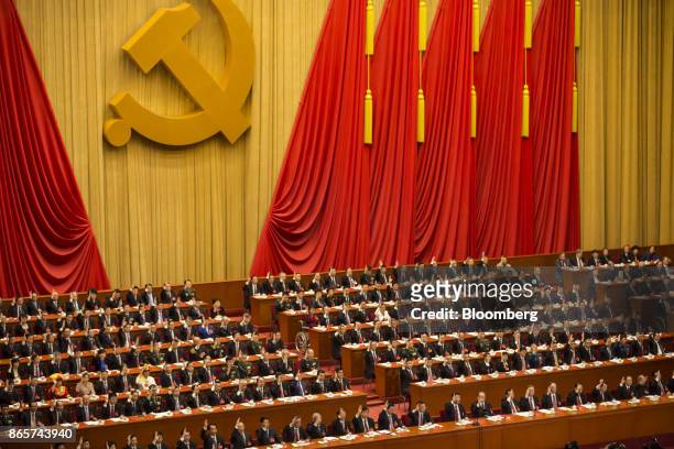 Party leaders and delegates raise their hands to indicate their votes during the closing session of the 19th National Congress of the Communist Party...