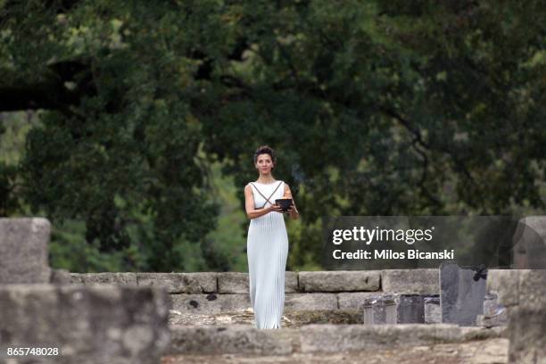 High priestess passes the Olympic flame at the Temple of Hera during a lighting ceremony of the Olympic flame in ancient Olympia on October 24, 2017...