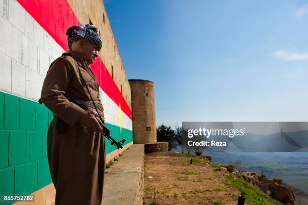 Peshmerga poses in front of a wall with a large fresco of the flag of Kurdistan. The fort overlooks Artush, a major oil refinery....