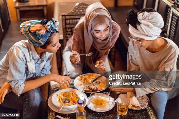 muslim young women having a lunch break together in an arab restaurant - moroccan culture stock pictures, royalty-free photos & images