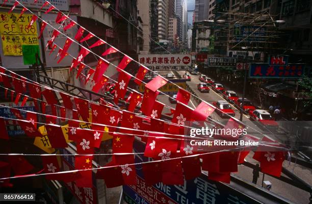 The flags of Hong Kong and Peoples' Republic of China fly together above the streets of Central, the day after the Handover of sovereignty from...
