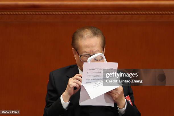 China's former president Jiang Zemin reads the file with a magnifying glass during the closing of the 19th Communist Party Congress at the Great Hall...