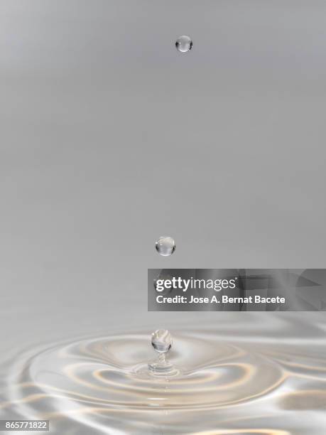 group of drops on line suspended in the air, falling down on a water surface that forms figures and abstract forms, on a gray background - onde sinusoïdale photos et images de collection