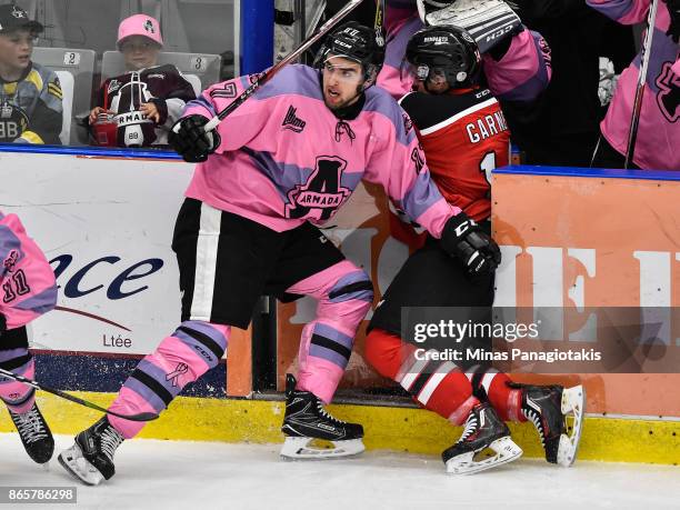 Thomas Ethier of the Blainville-Boisbriand Armada checks Olivier Garneau of the Quebec Remparts through the bench door during the QMJHL game at...