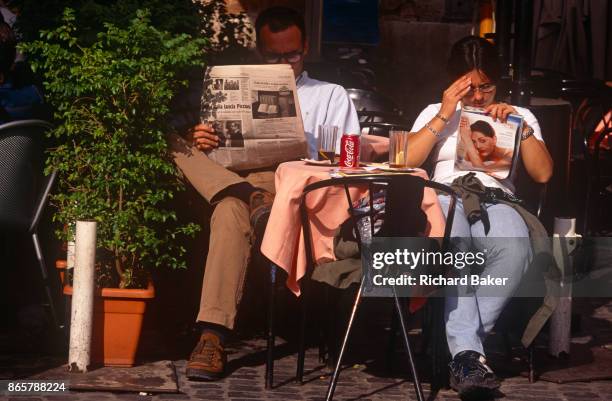 Cafe couple read a copy of Correre della Sera newspaper and a womens' magazine in the Italian capital, on 3rd November 1999, in Rome, Italy.