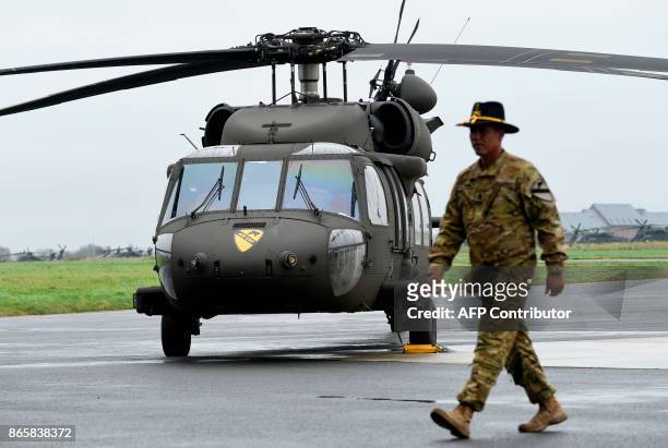 Soldier of the US Army 1st Cavalry Brigade, 1st Cavalry Division, walks past a UH-60 Black Hawk helicopter on the tarmac at Shape Airfield at...