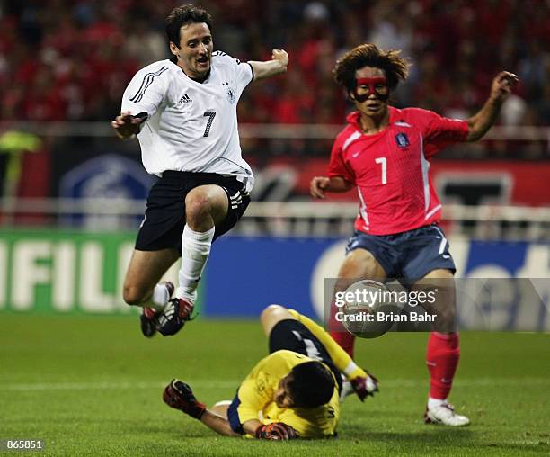 Oliver Neuville of Germany hurdles the challenge of goalkeeper Woon Jae Lee of South Korea as Tae Young Kim looks on during the FIFA World Cup Finals...