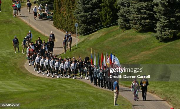 Cheryl Lee and Mark Lee Jr. Walk onto the first tee during the trophy ceremony during the first round of the Presidents Cup at Liberty National Golf...