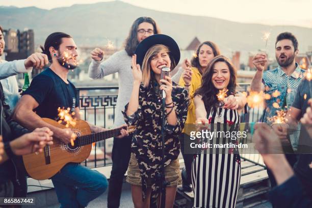 vrienden op het dak een muziekband beluisteren - performance group stockfoto's en -beelden