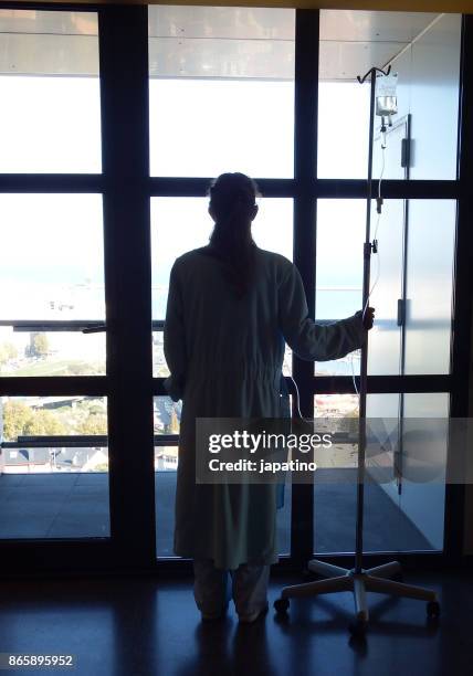 a sick woman at the hospital looks out the window while receiving drip medication - ストレプトミセス ストックフォトと画像