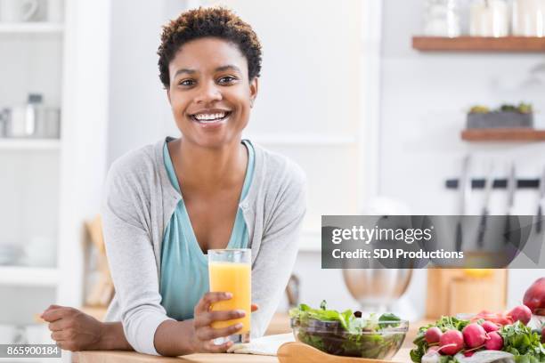 beautiful woman drink orange juice at kitchen counter - lap body area stock pictures, royalty-free photos & images