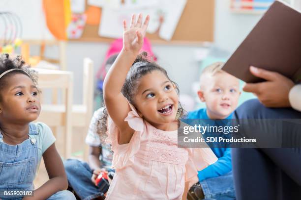 kleines mädchen hebt ihre hand in der klasse - cute girl toddler stock-fotos und bilder