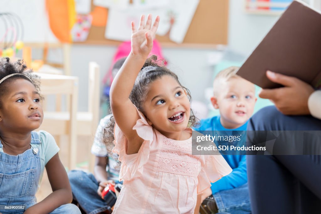 Little girl raises her hand in class