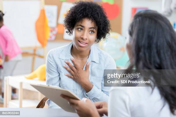 mamá preocupada habla con el maestro de su hijo - teacher meeting fotografías e imágenes de stock